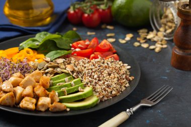 Kinoalı salata, avokado ve tavuk. Ön manzara. Siyah bir tabakta servis edildi..