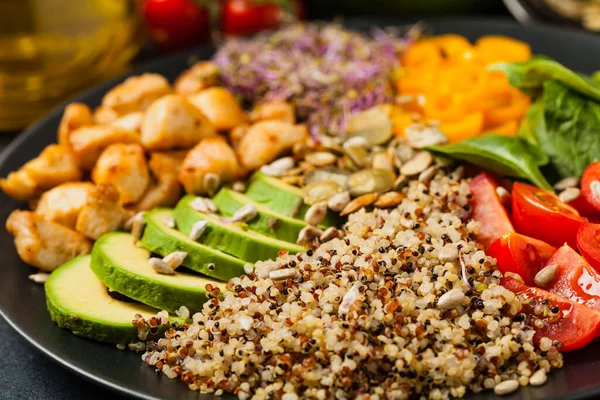 stock image Salad with quinoa, avocado and chicken. Front view. Served on a black plate.