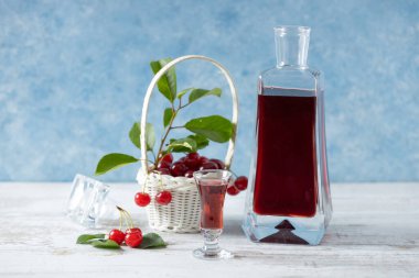 Sürahi ve bardakta kiraz likörü. Hafif arkaplan. Kirazlı pastayla servis edilir..