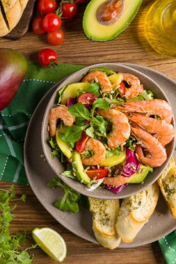 Karides, mango ve avokado ile bahar salatası. Kavrulmuş ayçekirdeği serpilmiş, kızarmış ekmeklerle dolu bir kasede servis edilir. Üst veya ön görünüm. 