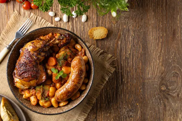 传统的法式一锅菜 鸡肉和白腊肠 卡苏莱天然木制背景 图库图片