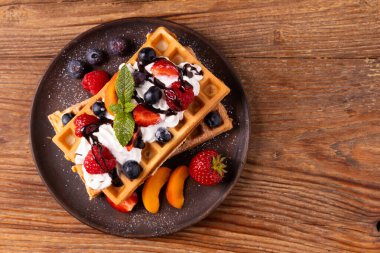 Krem şantili ve taze meyveli nefis ev yapımı waffle. Kağıt tepside ya da tabakta servis edilmiş. Ev yapımı fabrika. Üst veya ön görünüm.