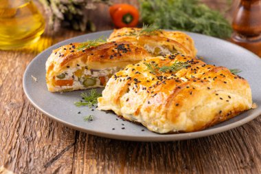 Puf böreğinin içinde sebzeli turta. Tabakta servis ediliyor. Üst veya ön görünüm.