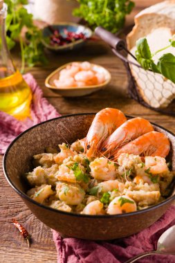 Geleneksel karidesli Portekiz ekmek çorbası. Acorda alentejana. Tahta bir masada kahverengi bir kasede servis edilmiş. Ön görünüm.