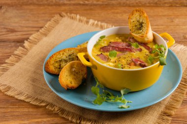 Geleneksel Polonya bezelye çorbası. Tütsülenmiş etle hazırlandı. İçinde kızarmış ekmek olan sarı bir kasede servis edilmiş. Ev yapımı. Üst veya üst görünüm.