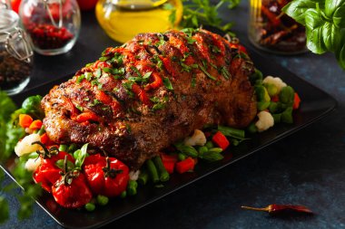 Tam kavrulmuş, domates, zeytin ve domuz boynuyla doldurulmuş. Karanlık arka plan, karanlık ruh hali.