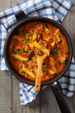 Geleneksel Kore Tteokbokki pilavı, tavuk, sebze ve mantarlı erişte. Tavada hazır. Ahşap arka plan. Üst görünüm.