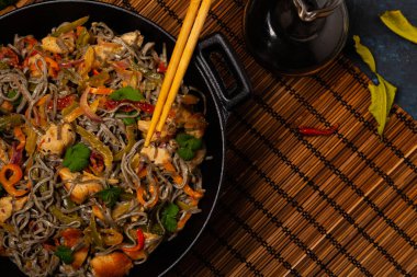 Siyah susamlı buğday eriştesi, tavuk ve sebzeli tavada kızartılmış. Üst görünüm.