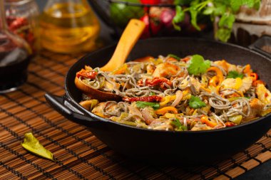 Siyah susamlı buğday eriştesi, tavuk ve sebzeli tavada kızartılmış. Ön görünüm.