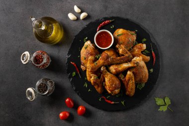 Fırında tavuk parçaları karışımı. Acı sos ya da patates kızartması ile servis edilir. Koyu arkaplan.