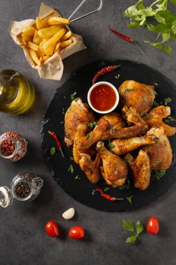Fırında tavuk parçaları karışımı. Acı sos ya da patates kızartması ile servis edilir. Koyu arkaplan.