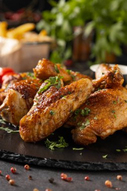 Fırında tavuk parçaları karışımı. Acı sos ya da patates kızartması ile servis edilir. Koyu arkaplan.