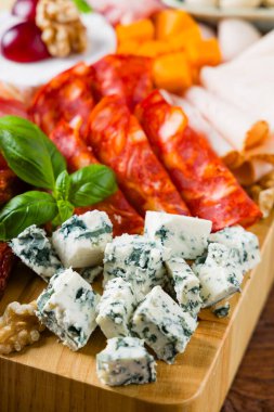 Et ve peynir tahtası. Pek çok ülkeden nefis peynirlerin ve sosislerin karışımı. Eklemek için zeytin, fındık ve sos. Tütsülenmiş ve olgunlaşmış soğuk kesimler, mavi peynirler, baharatlı ve hafif. Üst veya ön görünüm.