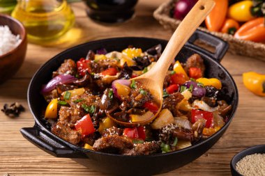 Geleneksel Asya tatlı ve ekşi domuz eti, kırmızı biber ve susamlı. Bir tavada hazır. Doğal ahşap arka plan.