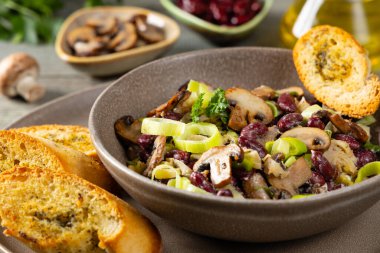 Kırmızı fasulye ve mantarlı bahar salatası. Yanında kızarmış ekmek ve sarımsaklı tereyağı var. Üst ya da üst görünüm. Gri arkaplan. 