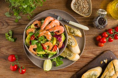 Karides, mango ve avokado ile bahar salatası. Kavrulmuş ayçekirdeği serpilmiş, kızarmış ekmeklerle dolu bir kasede servis edilir. Üst veya ön görünüm. 