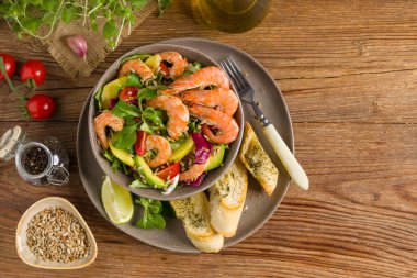 Karides, mango ve avokado ile bahar salatası. Kavrulmuş ayçekirdeği serpilmiş, kızarmış ekmeklerle dolu bir kasede servis edilir. Üst veya ön görünüm. 