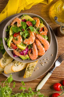 Karides, mango ve avokado ile bahar salatası. Kavrulmuş ayçekirdeği serpilmiş, kızarmış ekmeklerle dolu bir kasede servis edilir. Üst veya ön görünüm. 
