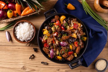 Geleneksel Asya tatlı ve ekşi domuz eti, kırmızı biber ve susamlı. Bir tavada hazır. Doğal ahşap arka plan.