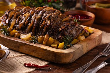 Bütün domuz boynunu kızarttım. Soğan dilimleriyle doldurulmuş. Fırında patatesle servis edilir. Doğal ahşap zemin