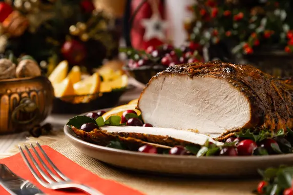 Fırında jambon. Noel süsü. Yabanmersini ve portakalla servis edilir. Pişirme sırasında iple bağlanmış. Tahta masa..