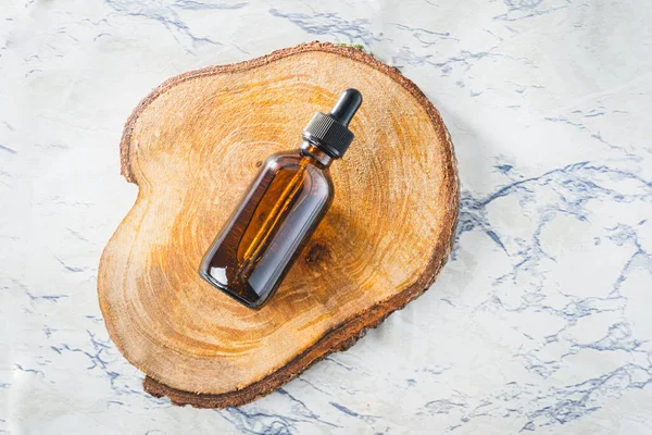 Top view of an essential oil dropper bottle on a cut wood background with copy space