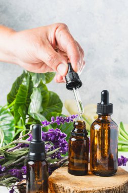 closeup of a hand with a dropper with lavender essential oils
