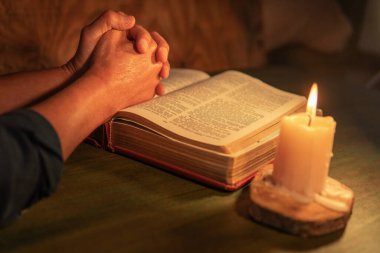 Mans dua duruşu bir İncil üzerinde mum ışığı ile