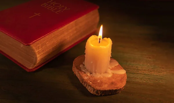 closeup of a closed bible and a lit candle
