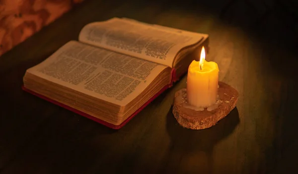 Biblia Oświetlona Światłem Świec Drewnianym Stole Pochodzenie Religijne — Zdjęcie stockowe