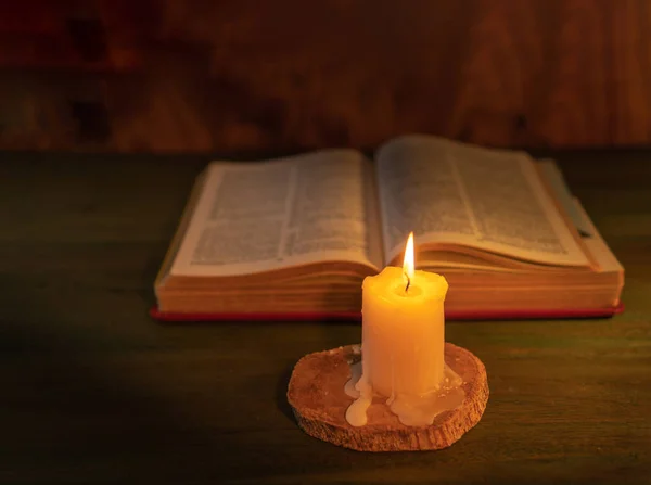 stock image candle illuminating a bible on a wooden background