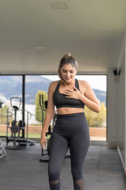 Spor giyim mağazasının önünde yürüyen gülümseyen Latin kadının sıradan portresi.