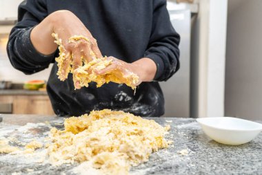 Pasta tarifi hazırlarken üzerine yapışan hamuru silen genç bir kadının elleri.