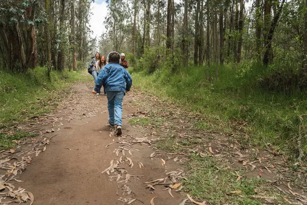 Bereketli bir ormanda yürüyüş sırasında aile üyelerine doğru koşan mutlu çocuk.