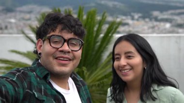 Mutlu Latin Amerikalı çift bulutlu bir günde akıllı telefonuyla selfie çekiyor.