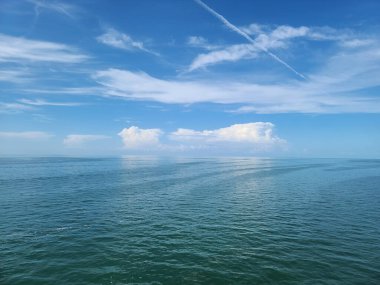 Durgun suları ile Florida Everglades deniz manzarası mavi gökyüzünü yansıtıyor ve ufuk üzerinde küçük adalar olan dağınık bulutlar.