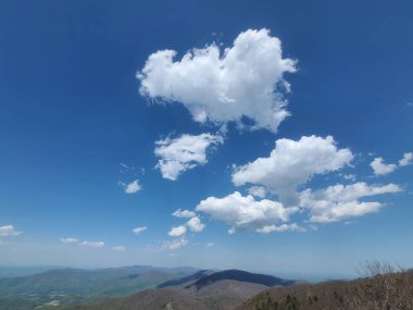 Shenandoah Ulusal Parkı 'nda dağınık beyaz bulutlarla dolu, parlak mavi bir gökyüzünün altındaki dağlık manzaralı bir manzara..