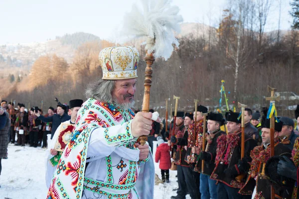 Kryvorivnia, Prykarpattia, Ukrayna, 19 Ocak 2019 Ukrayna 'nın Kryvorivnia dağlık köyünde geleneksel Epifani kutlamaları. Geleneksel etnik kıyafetli Hutsullar. Rahip Ivan Rybaruk.