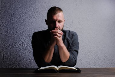 Bir adam masaya oturur ve kutsal kitabı okur. Ellerin bağlı dua et. Dua et ve Tanrı 'ya dua et.