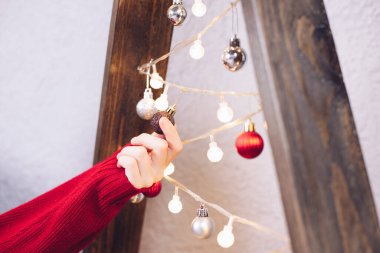 Noel ağacında çelenk. Noel ağacının parlak ışıkları. Bir el çelengi tutar