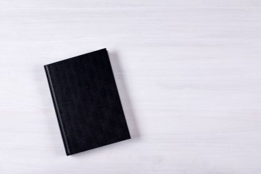 The book is on the table. On a white background. Closed black book