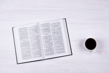 Masanın üzerinde açık bir İncil. Bir fincan kahve. Dua etmek için.