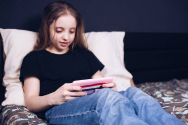 Genç bir çocuk telefonda video oyunları oynuyor. Aletlere bağımlılık. Kitabı yoksay