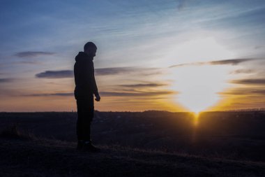 Dua et. Diz çöküp dua eden bir adam. Gökyüzü ve günbatımının arka planına karşı. Günahların ve pişmanlıkların bağışlanması. Paskalya