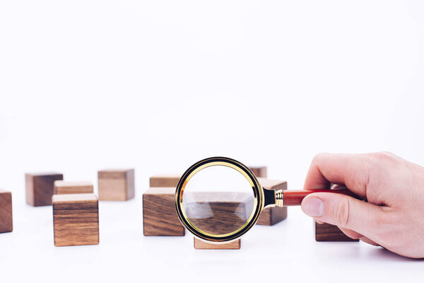Scattered wooden cubes on a white background. Blocks. Magnifying glass. Research and meticulousness. Detective