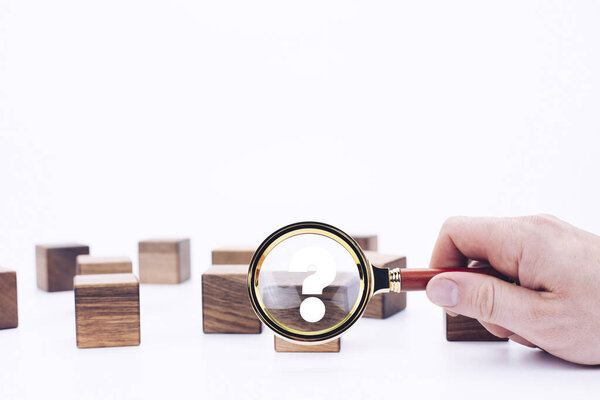 Scattered wooden cubes on a white background. Blocks. Magnifying glass. Research and meticulousness. Detective. Question mark.