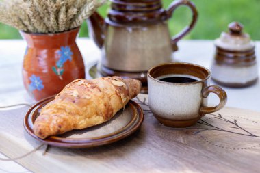 Mutfak tahtasındaki kruvasan. Çaydanlık ve çay kahvesi masanın üstünde. Sürahide bir buket kuru mısır. Sabah kahvaltı ettim.