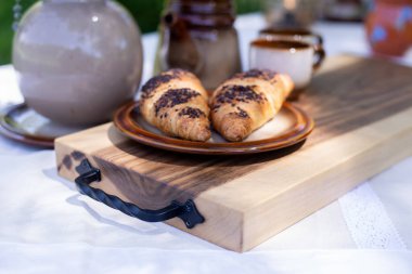 Kruvasan ve bir fincan kahve masanın üstünde. Mutfak tahtası ahşaptır. Kahvaltı..