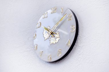 Epoksi reçineden yapılmış yuvarlak duvar saati. Saatli eller ve numaralar. Beyaz bir duvarda