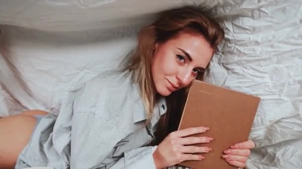 Мила Блондинка Білій Сорочці Ліжку Домашній Спальні Читає Книгу Модель — стокове відео